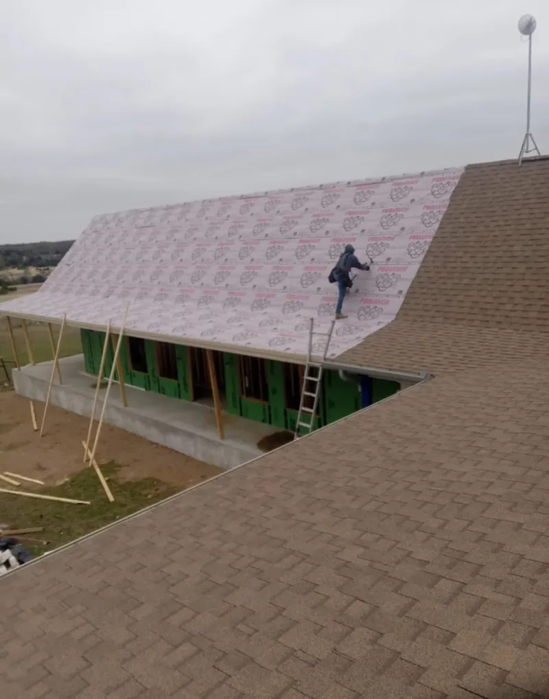 Worker preparing underlayment for a metal roof installation in Newport